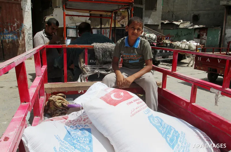 Palestinians receive Turkish aid at an aid distribution centre of the United Nations Relief and Works Agency (UNRWA) in the southern Gaza Strip town of Rafah, on July 18, 2016. Photo by Abed Rahim Khatib