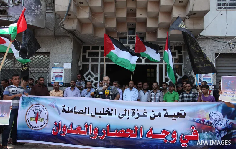 Palestinians hold banners and flags during a protest to solidarity with Hebron besieged by the Israeli occupation in Gaza city on July 20, 2016. Photo by Ashraf Amra