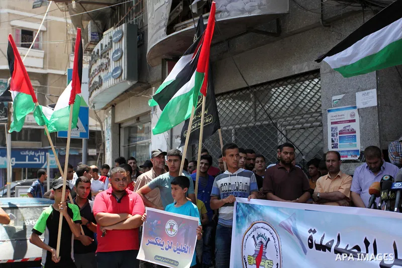 Palestinians hold banners and flags during a protest to solidarity with Hebron besieged by the Israeli occupation in Gaza city on July 20, 2016. Photo by Ashraf Amra