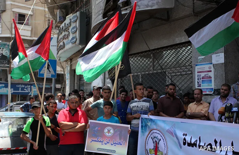 Palestinians hold banners and flags during a protest to solidarity with Hebron besieged by the Israeli occupation in Gaza city on July 20, 2016. Photo by Ashraf Amra