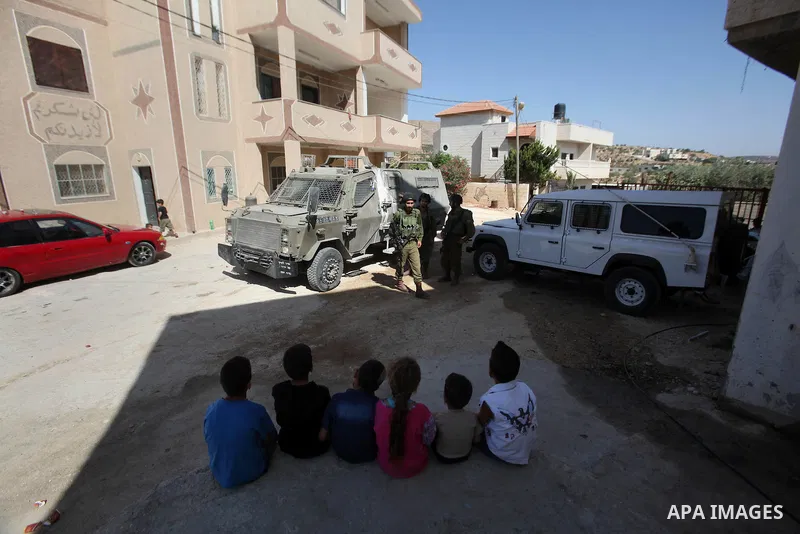 Israeli soldiers stand guard as they inspect a damaged house following a blaze overnight in the village of Duma in the Israeli-occupied West Bank on July 20, 2016. The house is located in the Palestinian village where an...