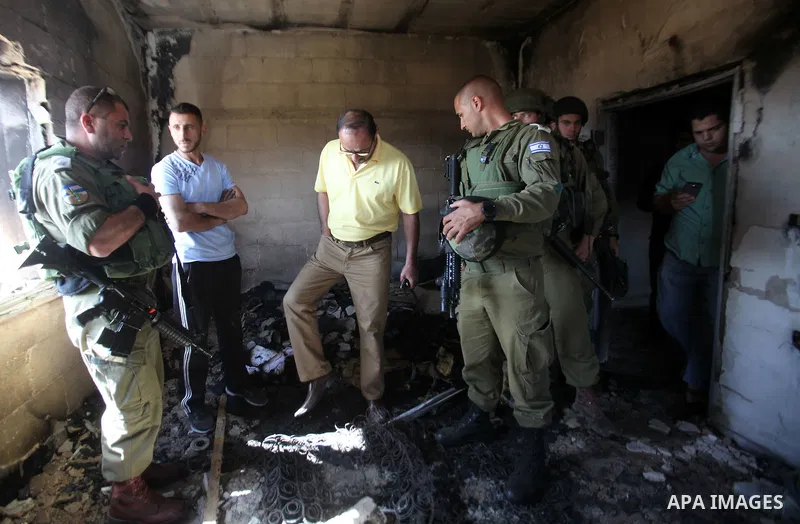Israeli soldiers and Palestinians inspect a damaged house following a blaze overnight in the village of Duma in the Israeli-occupied West Bank on July 20, 2016. The house is located in the Palestinian village where an ar...