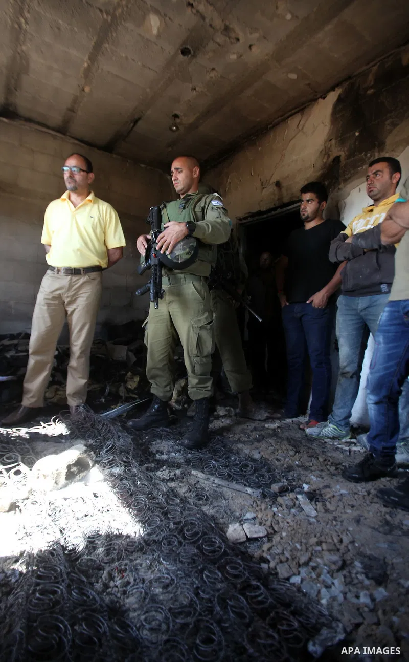 Israeli soldiers and Palestinians inspect a damaged house following a blaze overnight in the village of Duma in the Israeli-occupied West Bank on July 20, 2016. The house is located in the Palestinian village where an ar...