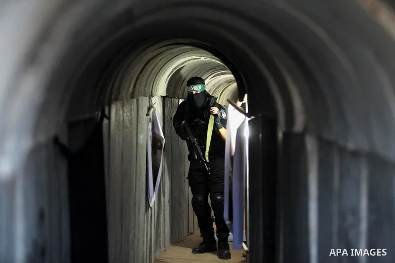 A member of the Ezzedine al-Qassam Brigades, the military wing of the Palestinian Islamist movement Hamas, walks inside a tunnel used for military exercises during a weapon exhibition at a Hamas-run youth summer camp, in...