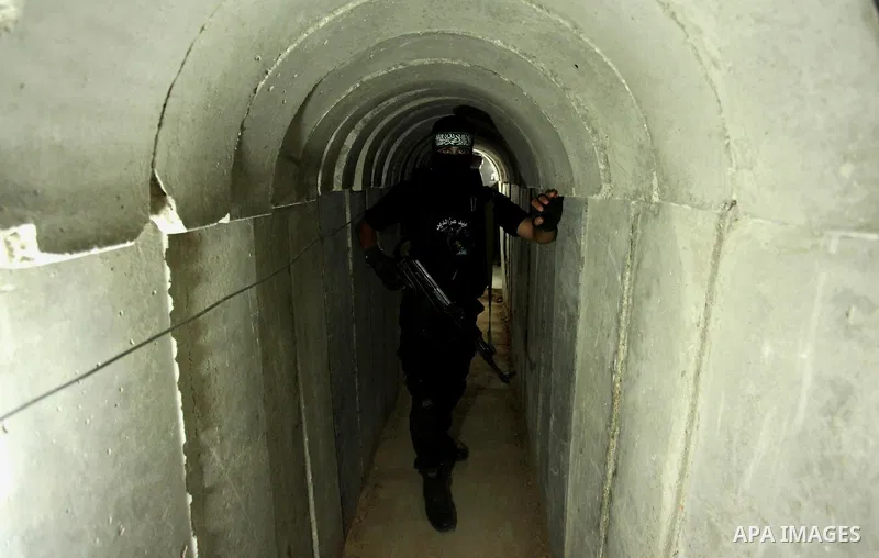 A member of the Ezzedine al-Qassam Brigades, the military wing of the Palestinian Islamist movement Hamas, walks inside a tunnel used for military exercises during a weapon exhibition at a Hamas-run youth summer camp, in...
