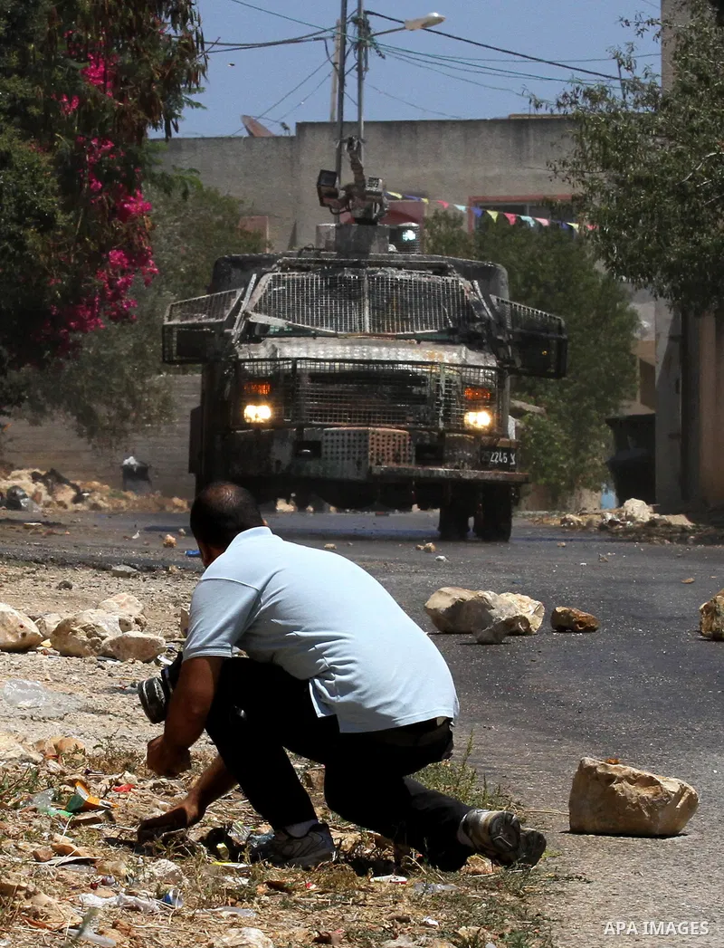 A Palestinian protester collects stones to throw towards Israeli security forces during clashes following the weekly demonstration against the expropriation of Palestinian land by Israel in the village of Kfar Qaddum, ne...