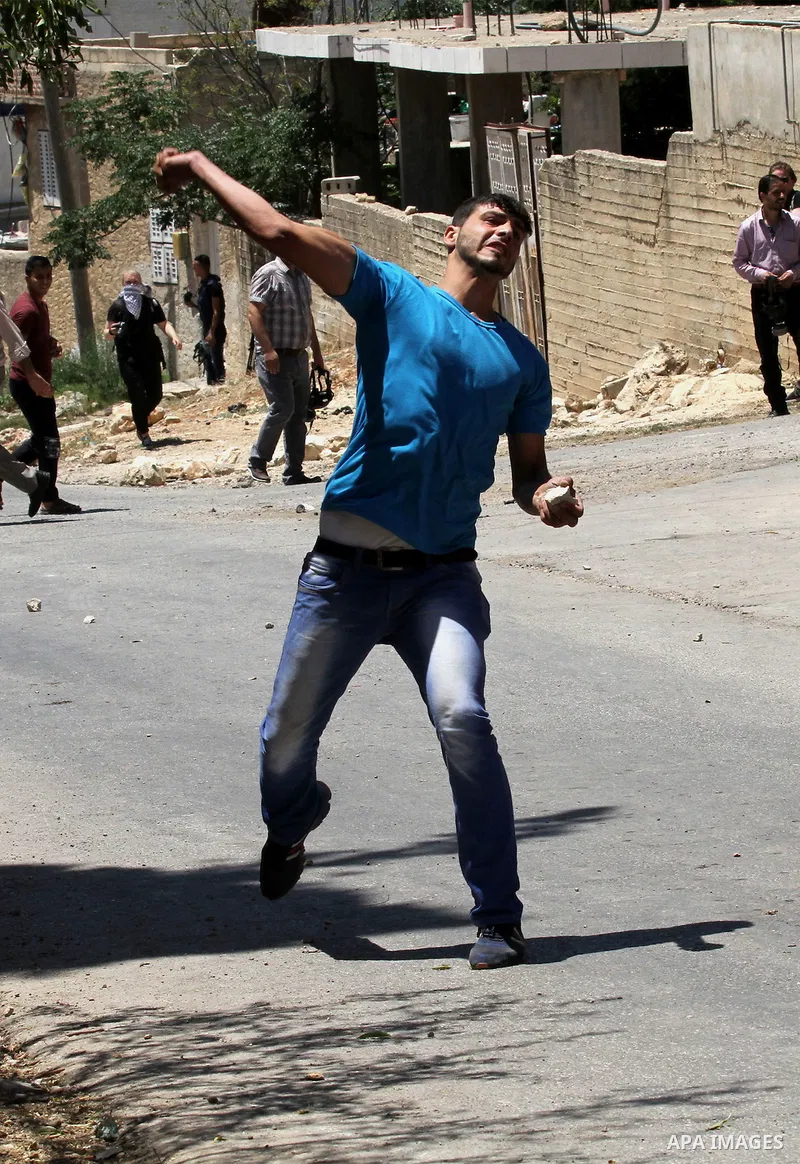 A Palestinian protester throws stones towards Israeli security forces during clashes following the weekly demonstration against the expropriation of Palestinian land by Israel in the village of Kfar Qaddum, near Nablus,...