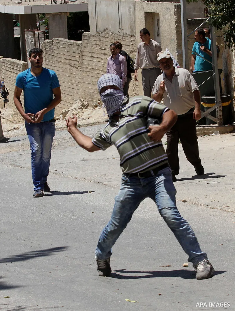A Palestinian protester throws stones towards Israeli security forces during clashes following the weekly demonstration against the expropriation of Palestinian land by Israel in the village of Kfar Qaddum, near Nablus,...