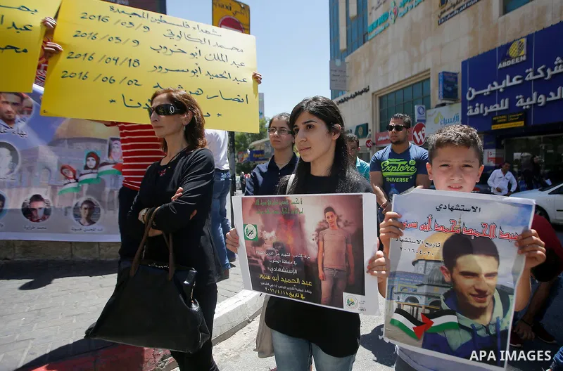 Palestinians hold placards during a protest in the West Bank city of Hebron 23 July 2016. Palestinians from all over the West bank held protest to support Palestinians prisoners Bilal Kayyed and Mohammad and Mahmoud Balb...