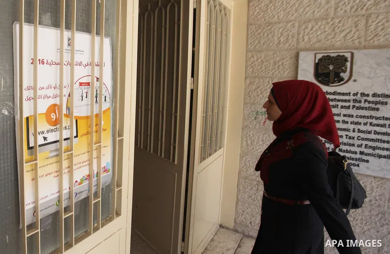 A Palestinian woman looks for her name on the registered voters' list at Voter registration centers in the West Bank city of Nablus on July 24, 2016. The Palestinian Central Elections Commission (CEO) announced Saturday...