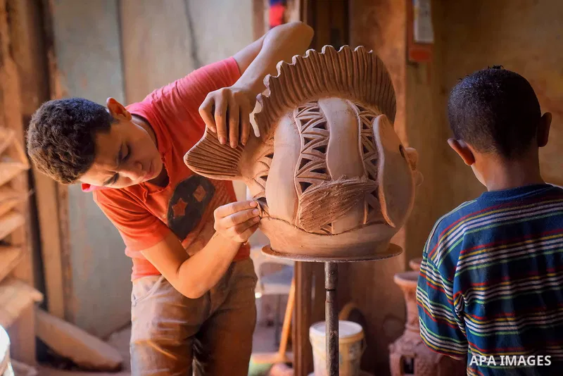 An Egyptian boy works at a pottery workshop in Cairo, on July 24, 2016. Pottery is an ancient and traditional craft in Egypt. Local workshops usually produce products such as bowls, pitchers, flower pots, and vases. Phot...
