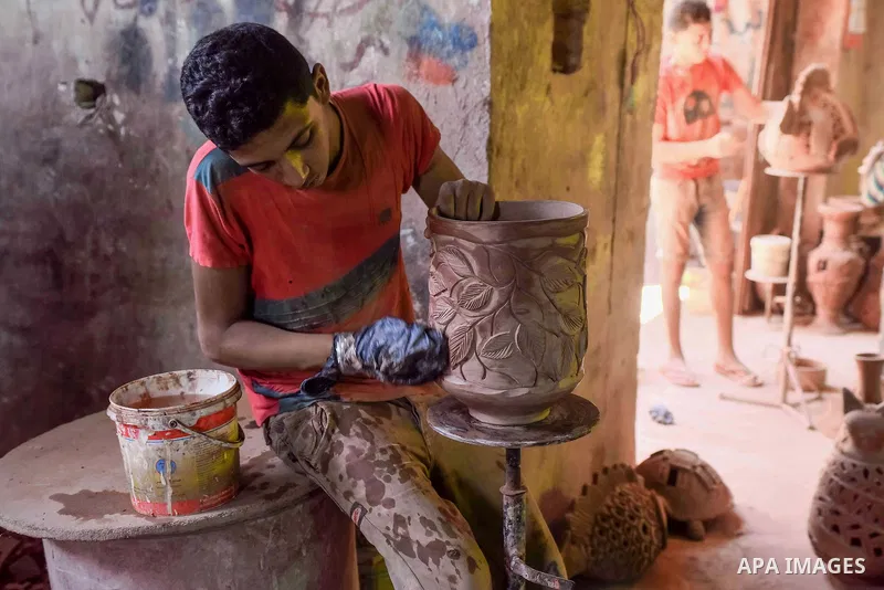 An Egyptian boy works at a pottery workshop in Cairo, on July 24, 2016. Pottery is an ancient and traditional craft in Egypt. Local workshops usually produce products such as bowls, pitchers, flower pots, and vases. Phot...