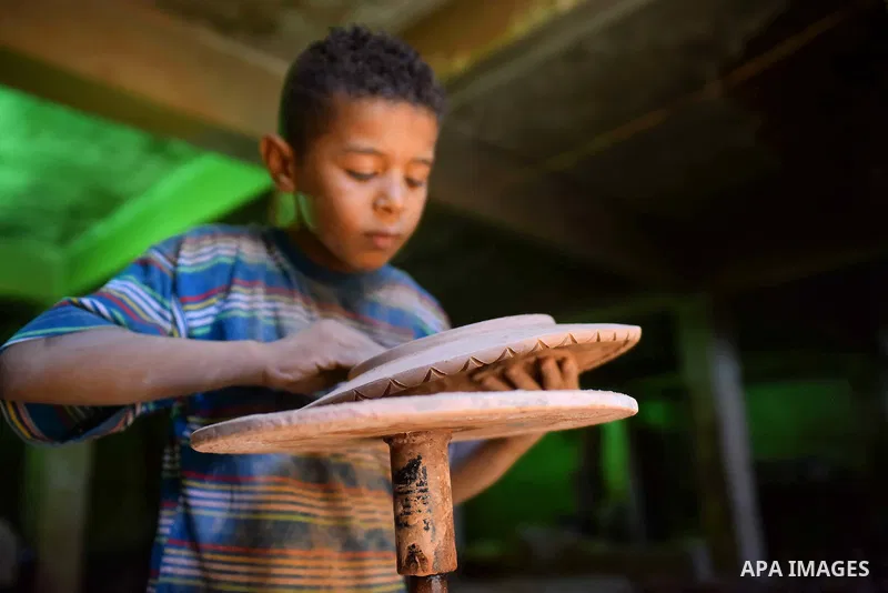 An Egyptian boy works at a pottery workshop in Cairo, on July 24, 2016. Pottery is an ancient and traditional craft in Egypt. Local workshops usually produce products such as bowls, pitchers, flower pots, and vases. Phot...