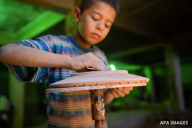 An Egyptian boy works at a pottery workshop in Cairo, on July 24, 2016. Pottery is an ancient and traditional craft in Egypt. Local workshops usually produce products such as bowls, pitchers, flower pots, and vases. Phot...