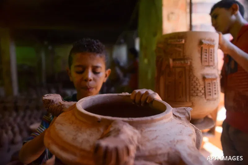 An Egyptian boy works at a pottery workshop in Cairo, on July 24, 2016. Pottery is an ancient and traditional craft in Egypt. Local workshops usually produce products such as bowls, pitchers, flower pots, and vases. Phot...