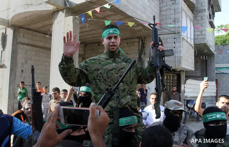 Freed Palestinian prisoner Mohammed al-Bashiti, who served 12 years in an Israeli jail after he was convicted of being a member of Hamas's armed wing, waves as he sits on the shoulders of a Hamas militant upon his releas...