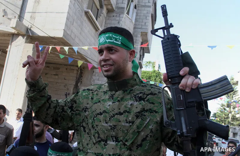 Freed Palestinian prisoner Mohammed al-Bashiti, who served 12 years in an Israeli jail after he was convicted of being a member of Hamas's armed wing, waves as he sits on the shoulders of a Hamas militant upon his releas...