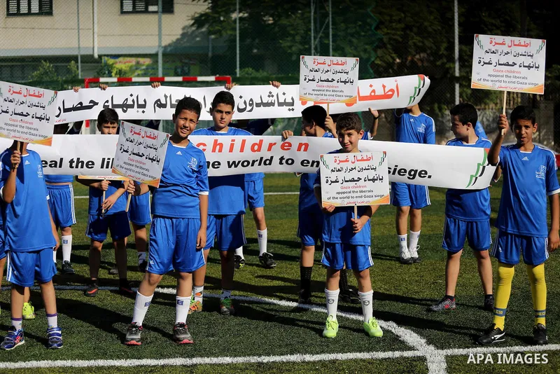 Palestinian boys hold placards demanding for end the siege during a training season for football school at Al Jazeera club in Gaza city, on July 26, 2016. Photo by Mohammed Asad