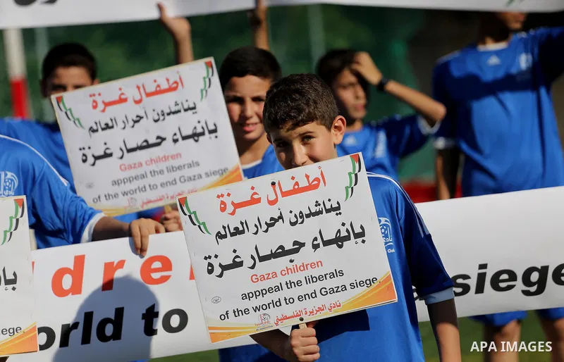 Palestinian boys hold placards demanding for end the siege during a training season for football school at Al Jazeera club in Gaza city, on July 26, 2016. Photo by Mohammed Asad