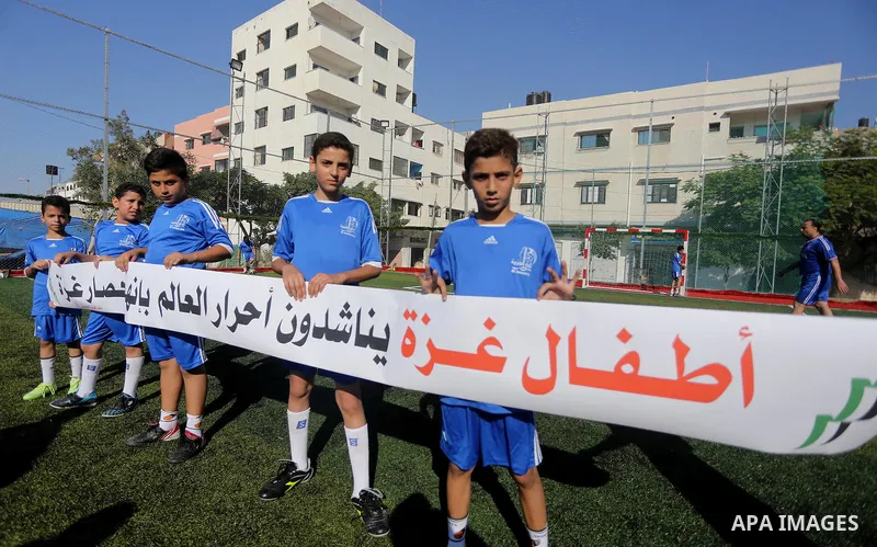 Palestinian boys hold placards demanding for end the siege during a training season for football school at Al Jazeera club in Gaza city, on July 26, 2016. Photo by Mohammed Asad