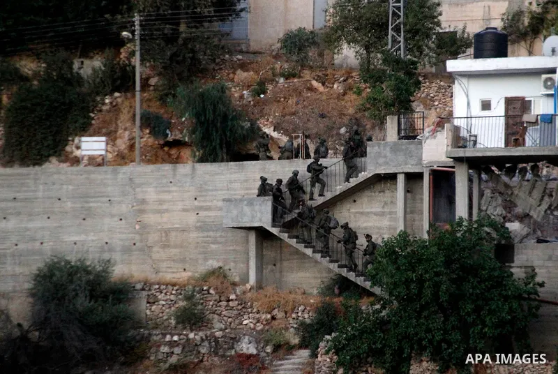 Israeli soldiers evacuate the body of Palestinian Mohammad al-Fakih after he was shot dead by the Israeli troops during a raid on a house in which he was hiding out in the West Bank village of Surif, near Hebron July 27,...