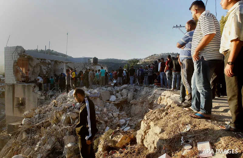 Palestinians check the clothes of Mohammad al-Fakih, who was shot dead by Israeli troops during a raid on a house in which he was hiding out, in the West Bank village of Surif, near Hebron July 27, 2016. Photo by Wisam H...