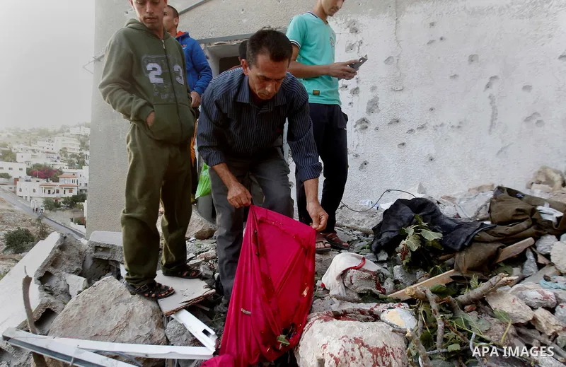 Palestinians check the clothes of Mohammad al-Fakih, who was shot dead by Israeli troops during a raid on a house in which he was hiding out, in the West Bank village of Surif, near Hebron July 27, 2016. Photo by Wisam H...