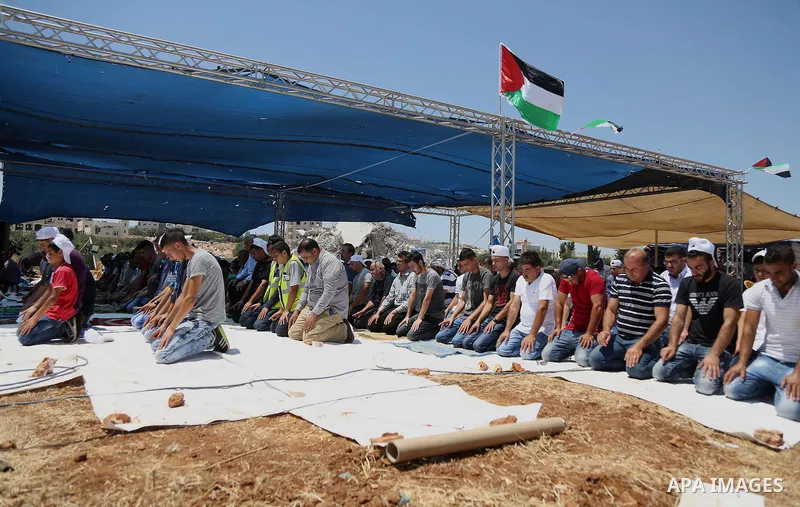 Palestinian Muslim worshippers perform the Friday prayer next to the rubble of the Palestinian homes that were destroyed by Israeli authorities three days before, on July 29, 2016 in the village of Qalandia, which is loc...