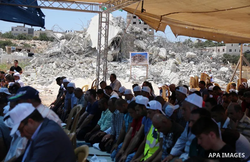 Palestinian Muslim worshippers perform the Friday prayer next to the rubble of the Palestinian homes that were destroyed by Israeli authorities three days before, on July 29, 2016 in the village of Qalandia, which is loc...