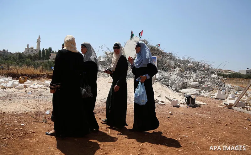 Palestinian Muslim worshippers perform the Friday prayer next to the rubble of the Palestinian homes that were destroyed by Israeli authorities three days before, on July 29, 2016 in the village of Qalandia, which is loc...