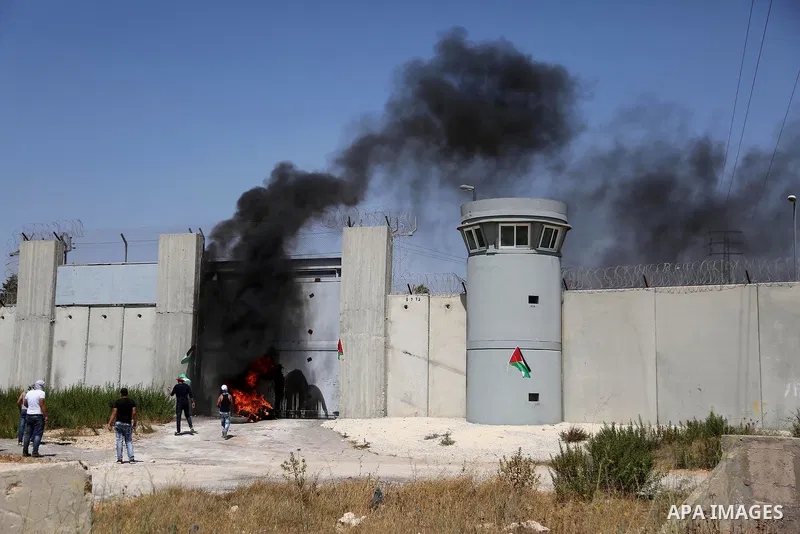 Palestinian youths burn tires and throw stones towards an Israeli military post following the Friday prayer on July 29, 2016 near Qalandia, which is located next to Israel's controversial separation barrier, between the...