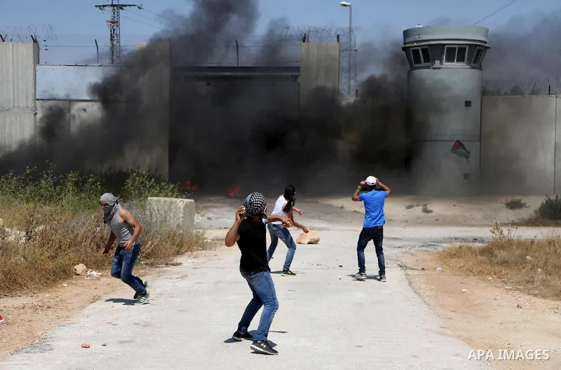 Palestinian youths burn tires and throw stones towards an Israeli military post following the Friday prayer on July 29, 2016 near Qalandia, which is located next to Israel's controversial separation barrier, between the...