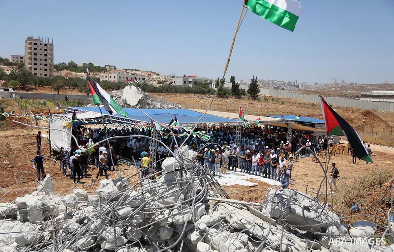 Palestinian Muslim worshippers perform the Friday prayer next to the rubble of the Palestinian homes that were destroyed by Israeli authorities three days before, on July 29, 2016 in the village of Qalandia, which is loc...