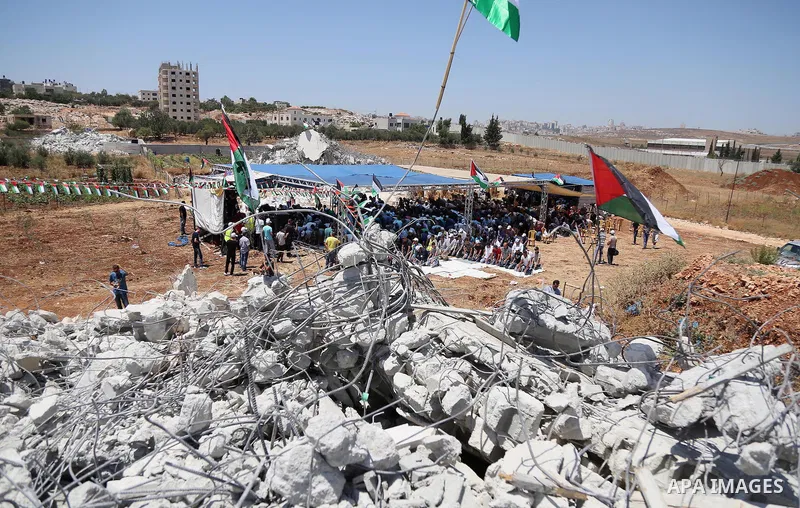 Palestinian Muslim worshippers perform the Friday prayer next to the rubble of the Palestinian homes that were destroyed by Israeli authorities three days before, on July 29, 2016 in the village of Qalandia, which is loc...