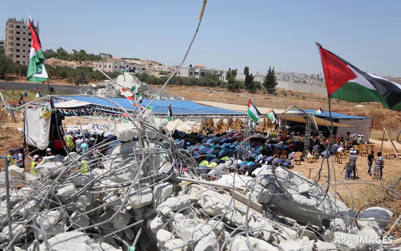 Palestinian Muslim worshippers perform the Friday prayer next to the rubble of the Palestinian homes that were destroyed by Israeli authorities three days before, on July 29, 2016 in the village of Qalandia, which is loc...