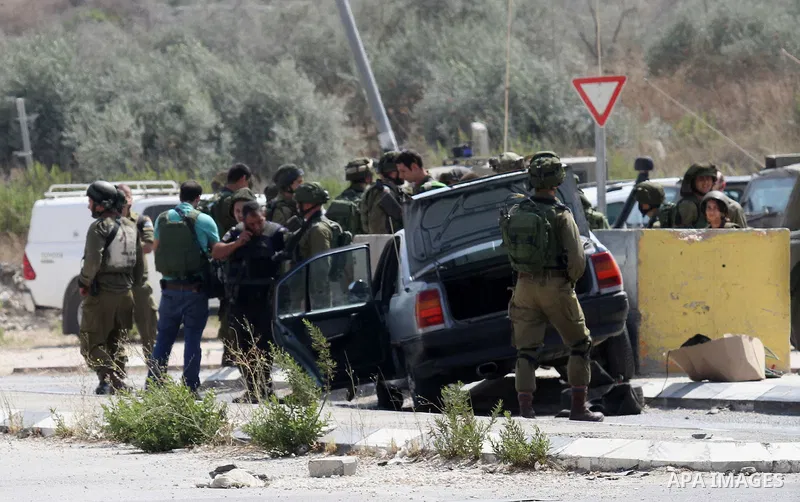 Israeli soldiers gather next to a vehicle belonging to a Palestinian man after he reportedly charged it into a group of soldiers at the Israeli army Hawara checkpoint near the city of Nablus in the occupied West Bank on...