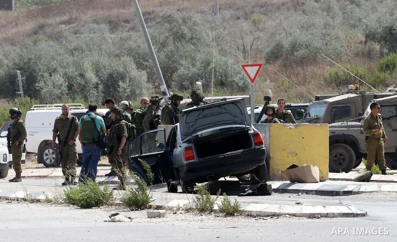 Israeli soldiers gather next to a vehicle belonging to a Palestinian man after he reportedly charged it into a group of soldiers at the Israeli army Hawara checkpoint near the city of Nablus in the occupied West Bank on...