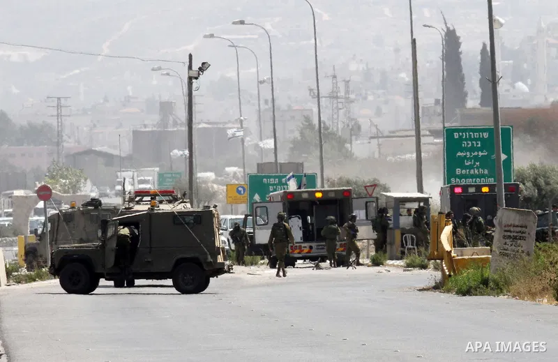 Israeli soldiers gather next to a vehicle belonging to a Palestinian man after he reportedly charged it into a group of soldiers at the Israeli army Hawara checkpoint near the city of Nablus in the occupied West Bank on...