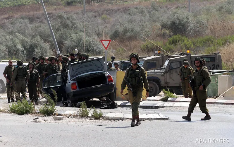 Israeli soldiers gather next to a vehicle belonging to a Palestinian man after he reportedly charged it into a group of soldiers at the Israeli army Hawara checkpoint near the city of Nablus in the occupied West Bank on...