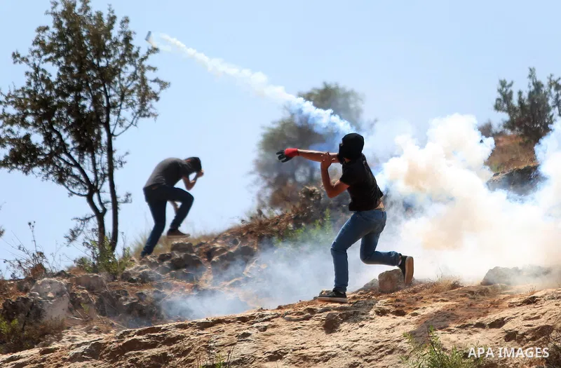 A Palestinian protester throws back a tear gas canister fired by Israeli security forces during clashes following a demonstration against the detention of Bilal Kayed a Palestinian prisoner on hunger strike, outside the...