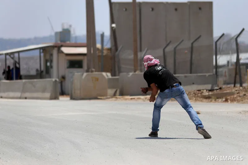 A Palestinian protester throws stones towards Israeli security forces during clashes following a demonstration against the detention of Bilal Kayed a Palestinian prisoner on hunger strike, outside the compound of the Isr...