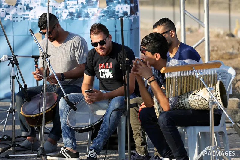 Palestinian band Dawaween, who were denied access to perform at a festival in Jerusalem, deliver a performance as part of a protest against the denial in Beit Hanun, near the Erez crossing point with Israel, in the north...