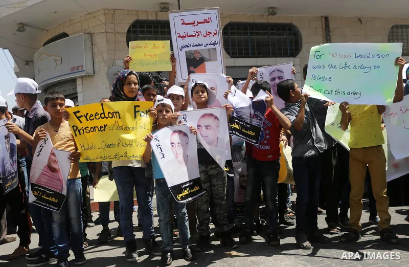 Palestinian demonstrators hold posters of Mohammad El Halabi, World Vision's manager of operations in Gaza who was accused by Israel of funnelling millions of dollars in aid money to Hamas, during a protest in solidarity...
