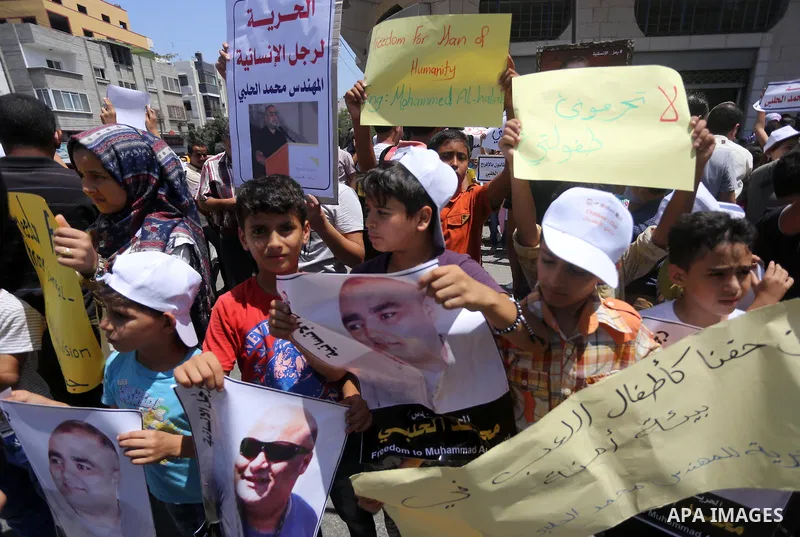 Palestinian demonstrators hold posters of Mohammad El Halabi, World Vision's manager of operations in Gaza who was accused by Israel of funnelling millions of dollars in aid money to Hamas, during a protest in solidarity...