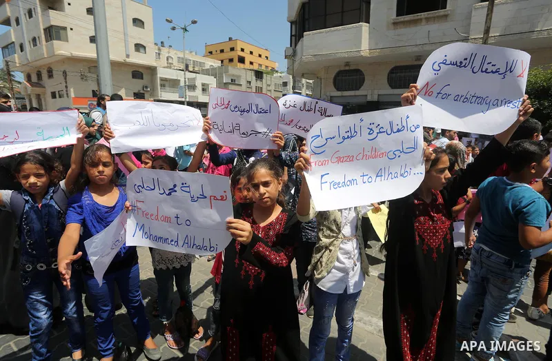 Palestinian demonstrators hold posters of Mohammad El Halabi, World Vision's manager of operations in Gaza who was accused by Israel of funnelling millions of dollars in aid money to Hamas, during a protest in solidarity...