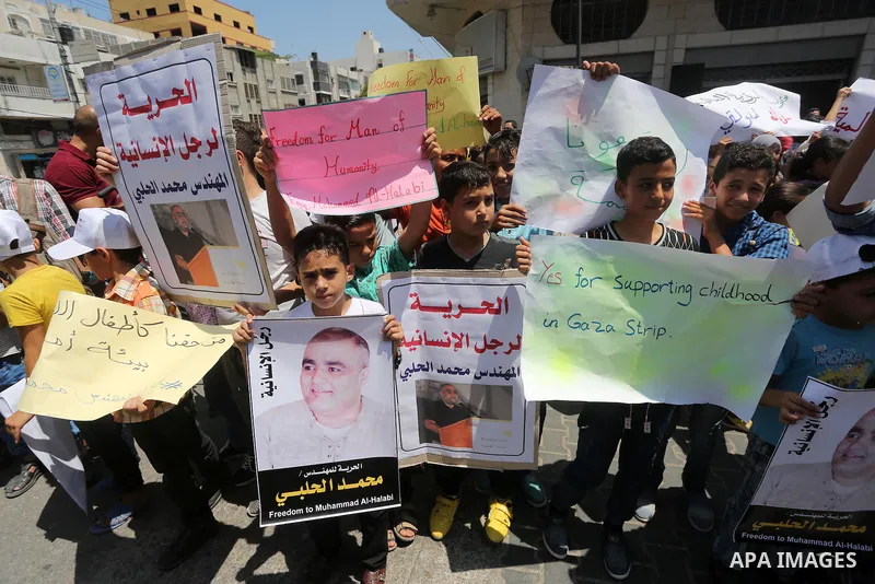 Palestinian demonstrators hold posters of Mohammad El Halabi, World Vision's manager of operations in Gaza who was accused by Israel of funnelling millions of dollars in aid money to Hamas, during a protest in solidarity...