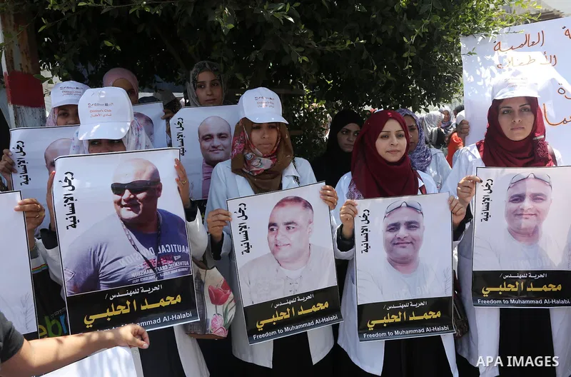 Palestinian demonstrators hold posters of Mohammad El Halabi, World Vision's manager of operations in Gaza who was accused by Israel of funnelling millions of dollars in aid money to Hamas, during a protest in solidarity...