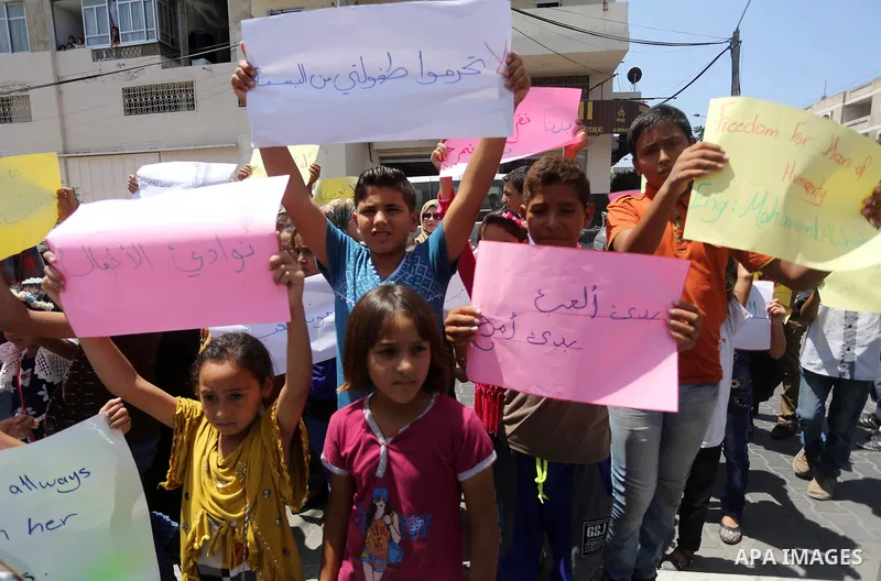 Palestinian demonstrators hold posters of Mohammad El Halabi, World Vision's manager of operations in Gaza who was accused by Israel of funnelling millions of dollars in aid money to Hamas, during a protest in solidarity...