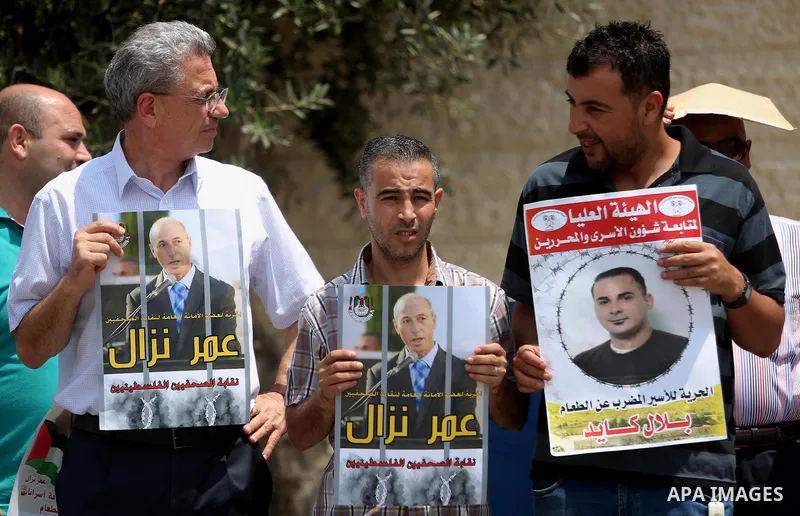 Palestinians take part during a protest calling for the release of Palestinian journalist Omar Nazzal and Bilal Kayed a Palestinian prisoner on hunger strike, in front of UN headquarters in the West Bank city of Ramallah...