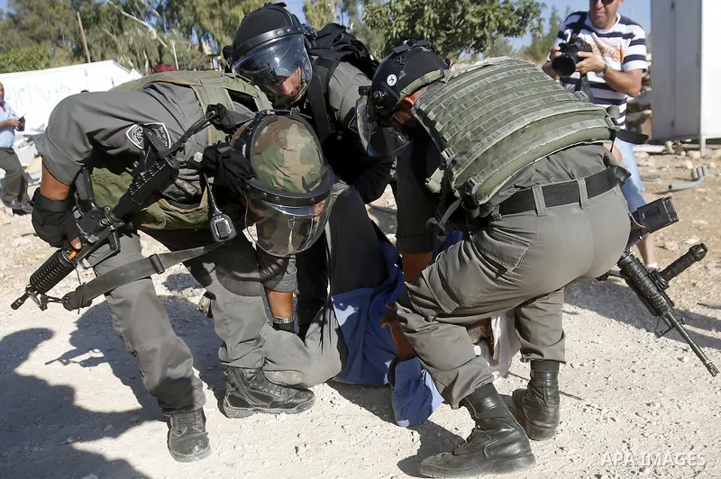 Israeli border policemen carry away a Palestinian man after Israeli troops demolished his shed near the West Bank village of Um AlKhair, south of Hebron August 9, 2016. Photo by Wisam Hashlamoun